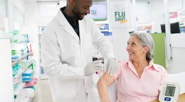 pharmacist administering vaccine to woman, blood pressure monitor on table, RPM 2