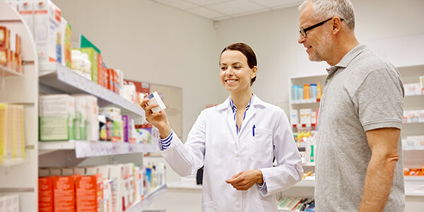 pharmacist showing drug to senior man at pharmacy